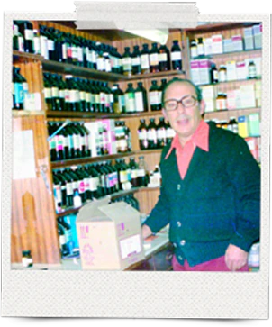 An archive photo of Basil Bennett, the chemist, smiling behind his pharmacy counter in front of shelves of medicine bottles